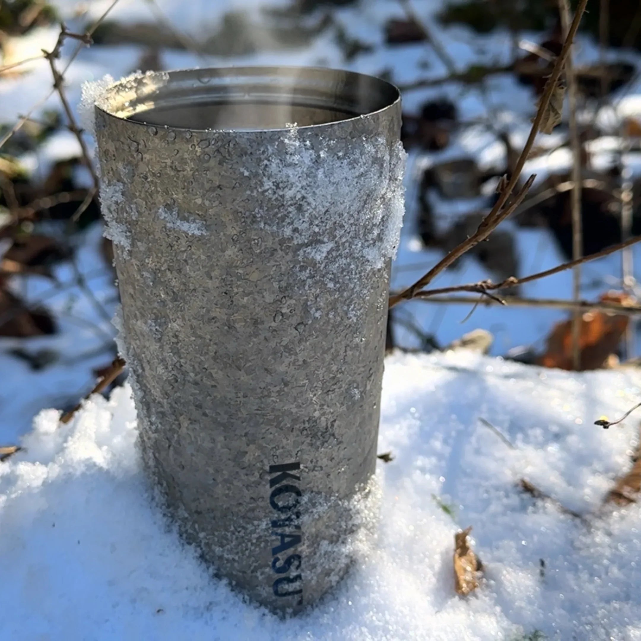 KOYASU 17oz Whole-Body Titanium Mug placed in snow, showing steam and outdoor cold resistance