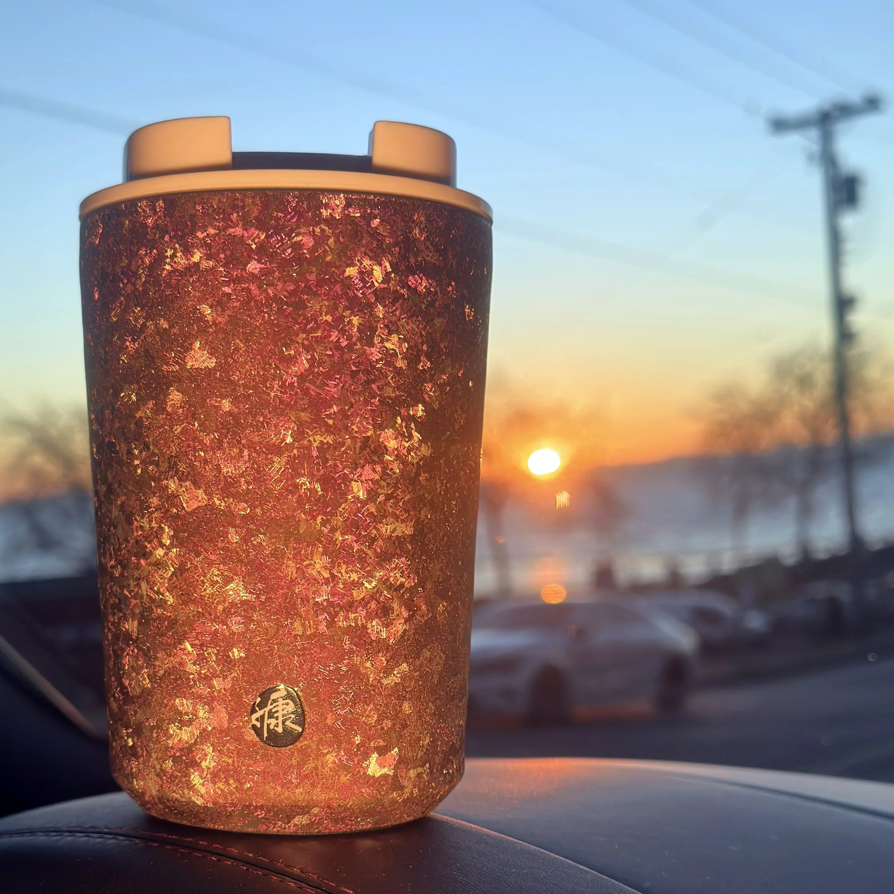 KOYASU Ti-Zen Dawn Pink Titanium Coffee Cup glowing in sunset light on car dashboard aesthetic gift