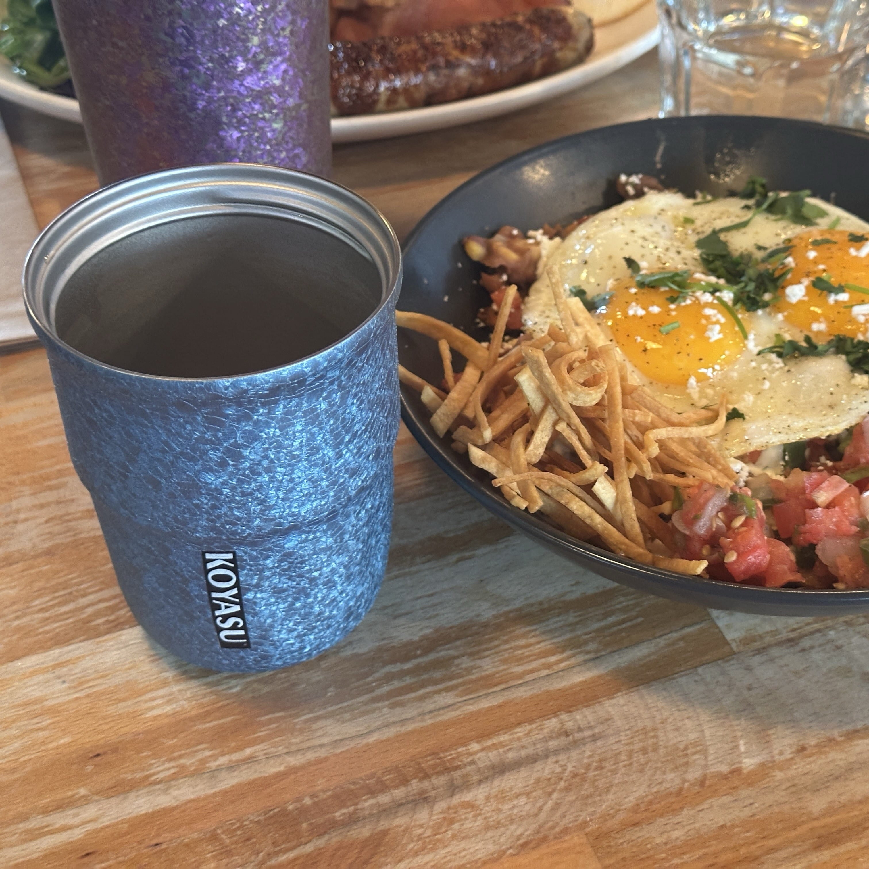 KOYASU 12oz titanium-lined cup-mug-tumbler-thermos-bottle in Cool Blue, shown on a brunch table beside a breakfast plate. Features uncoated interior for safe, pure flavor.
