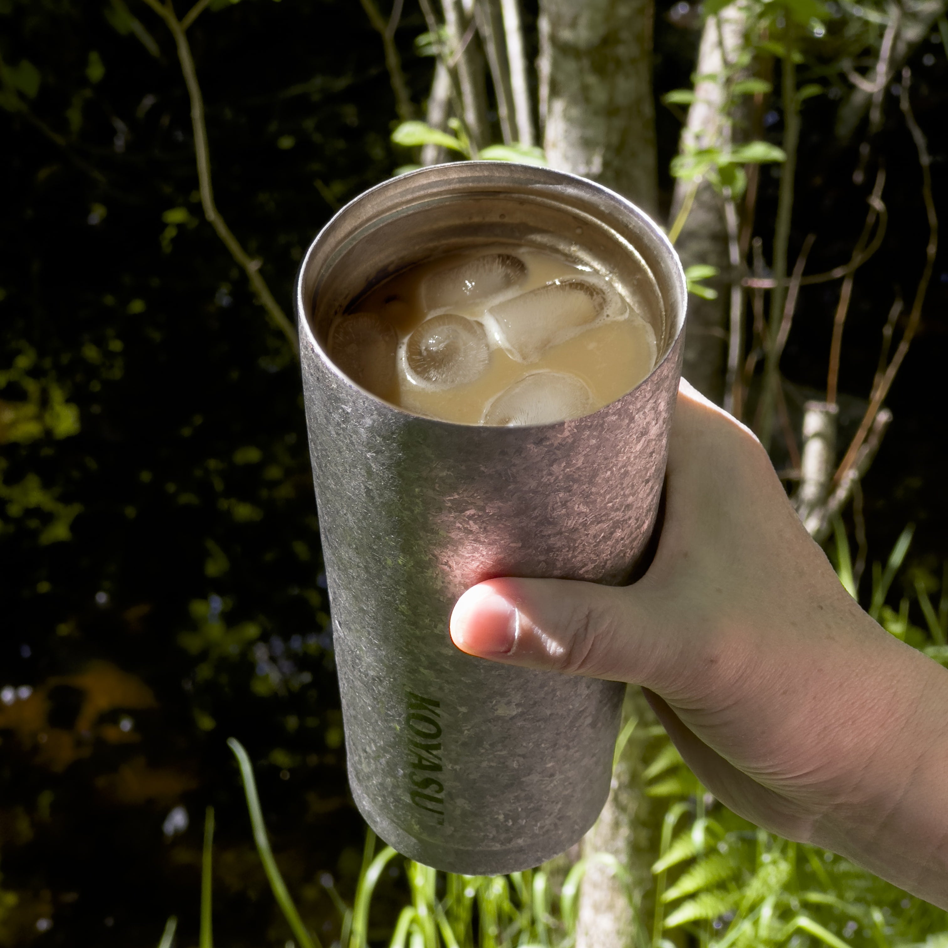 KOYASU 17oz Whole-Body Titanium Mug – handheld with iced coffee outdoors, lightweight hiking tumbler